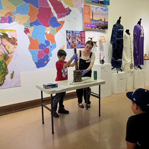Students learn to play a Jordan coffee-drum from Sue Koenig's Window to the World during a fieldtrip