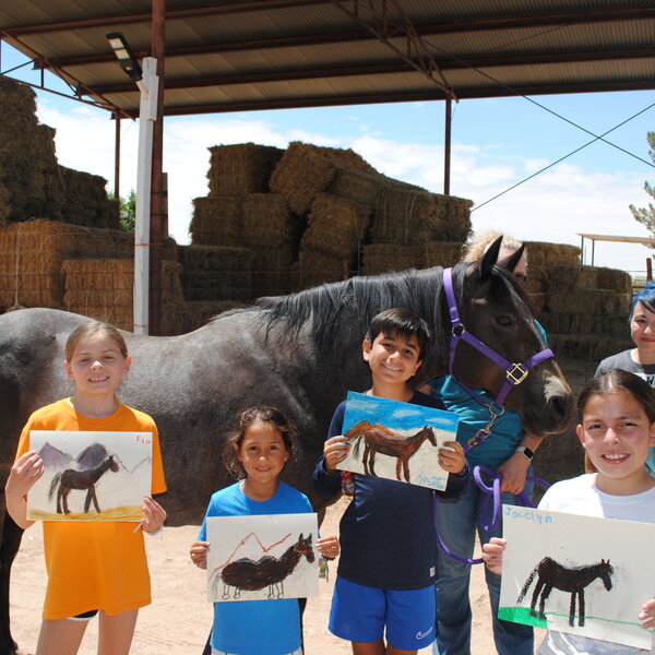 Children from the YWCA stand next to the horse they drew from Compadres Horse therapy. Standing alongside is El Paso artist Blanca Estrada who taught them how to draw the horse.